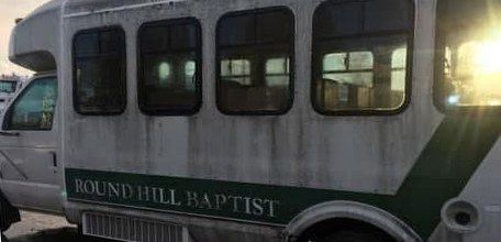 White shuttle bus with a dirty, streaked side