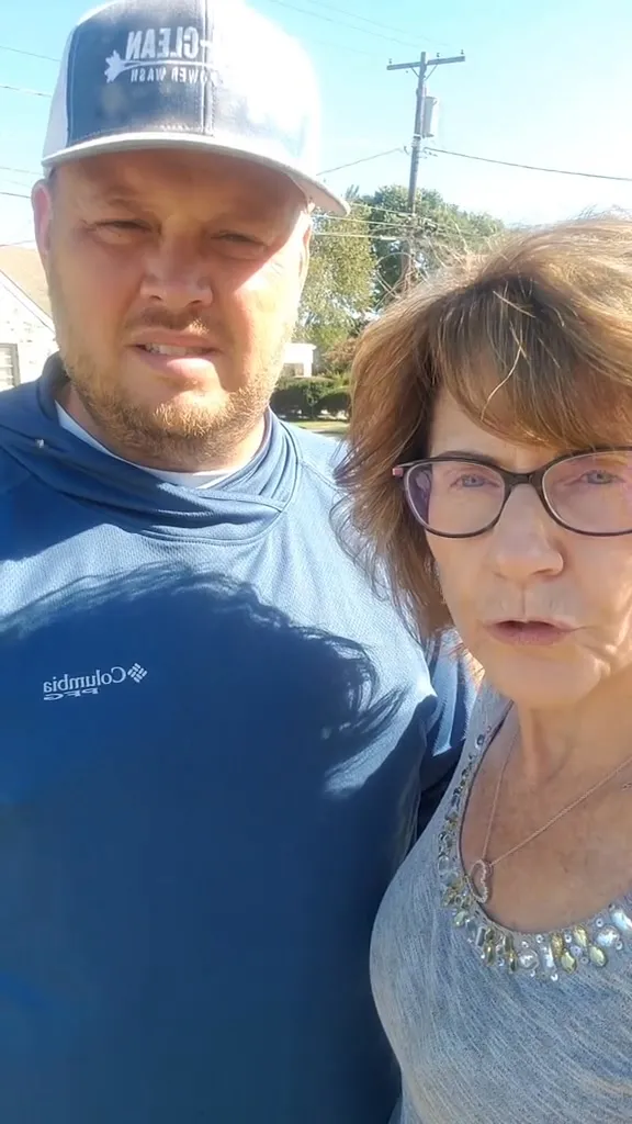 A homeowner and a man in a Chem-Clean cap stand together outside on a sunny day, about to talk to the camera