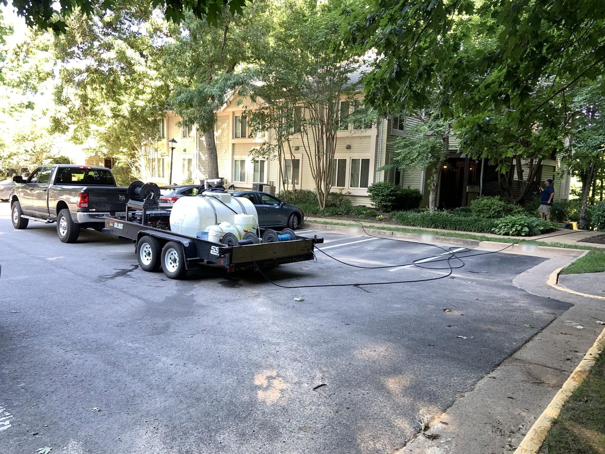 Pickup and wash trailer with tank and hose reels set up beside a residential building