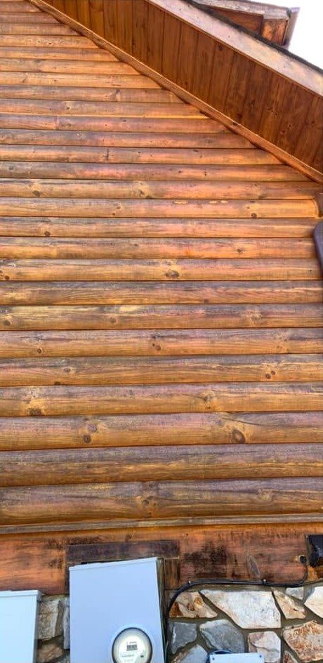 The same log gable wall with clean golden logs after washing