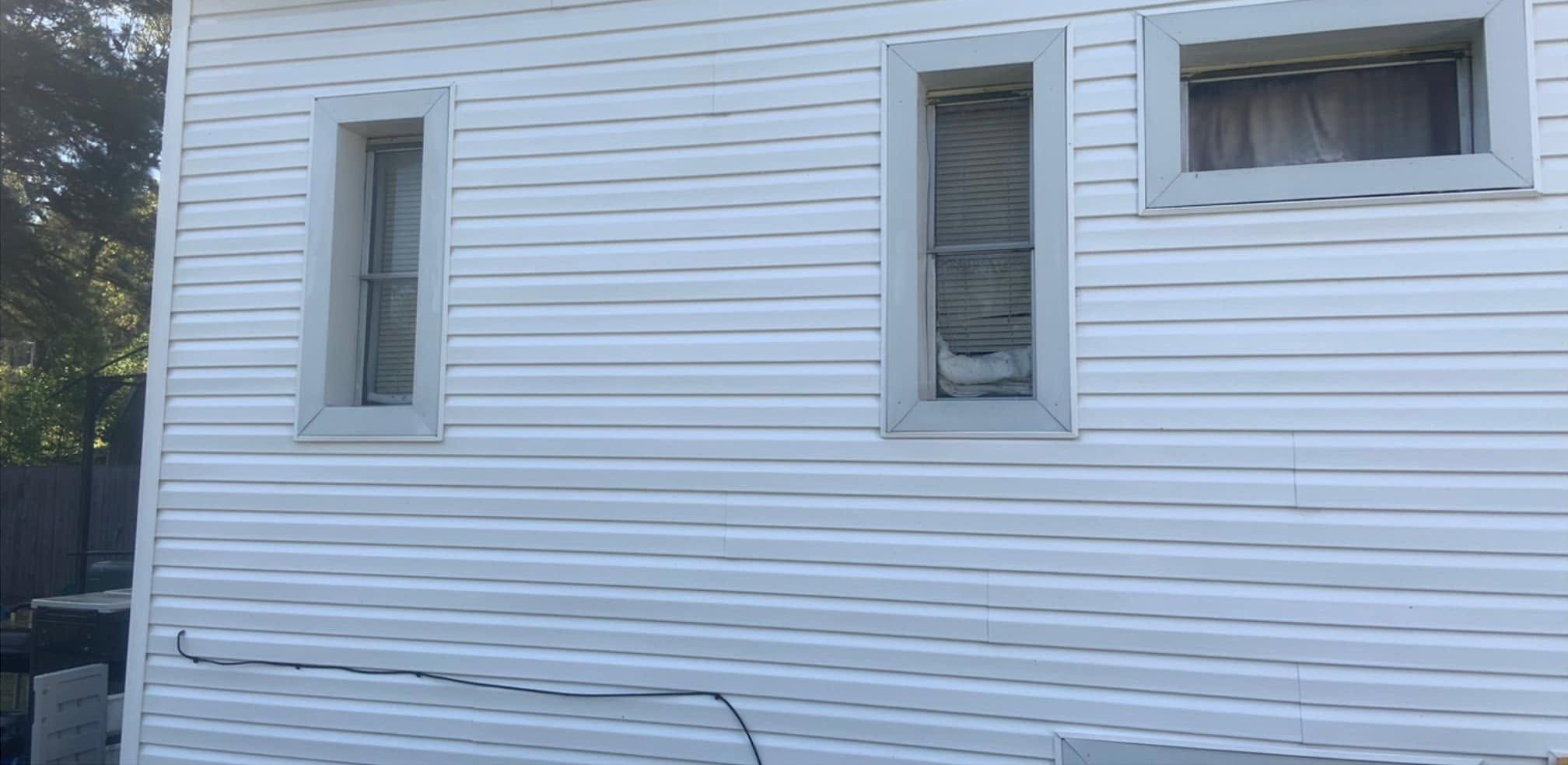The same wall after washing, clean white siding around the windows