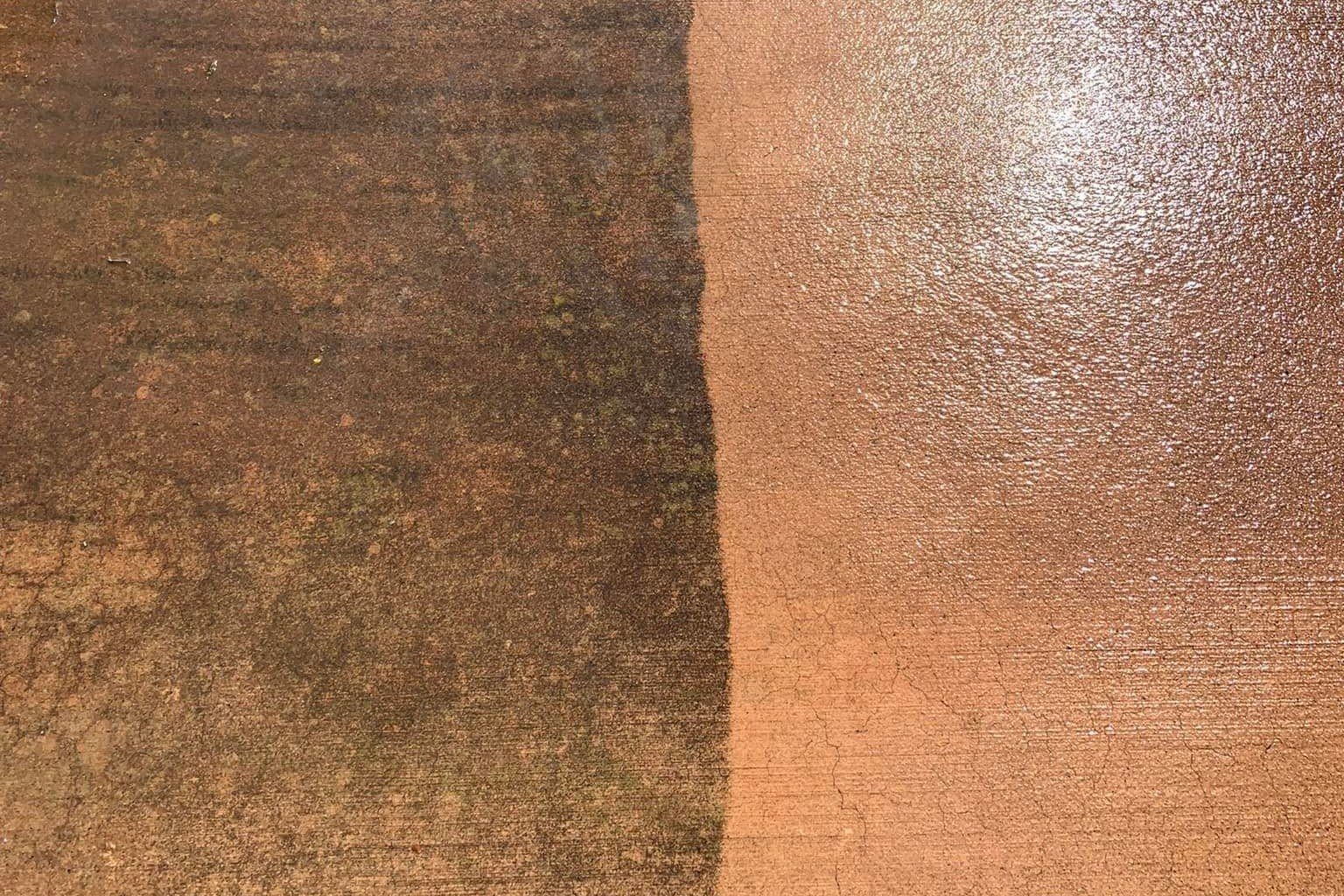 Concrete half cleaned, dark algae stains on one side and bright clean surface on the other