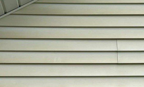 Yellowed vinyl siding under the soffit of a gable wall before washing