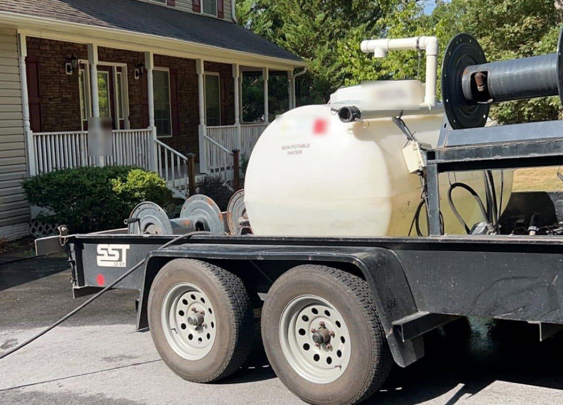 Wash trailer with water tank and hose reels parked in a home driveway