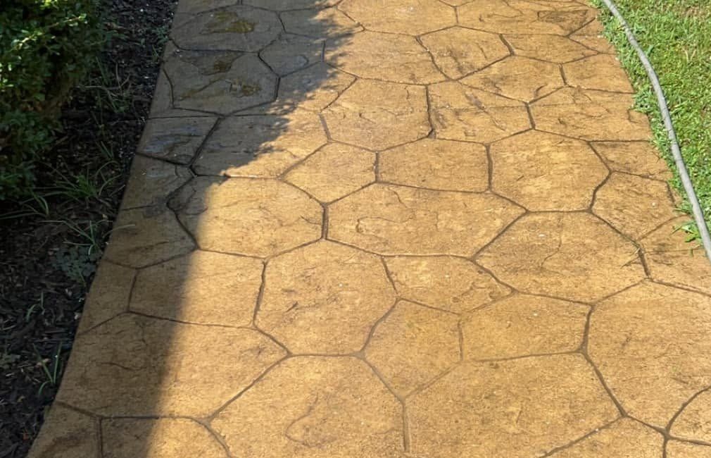 Stamped concrete walkway in a stone pattern with a hose laid along its edge