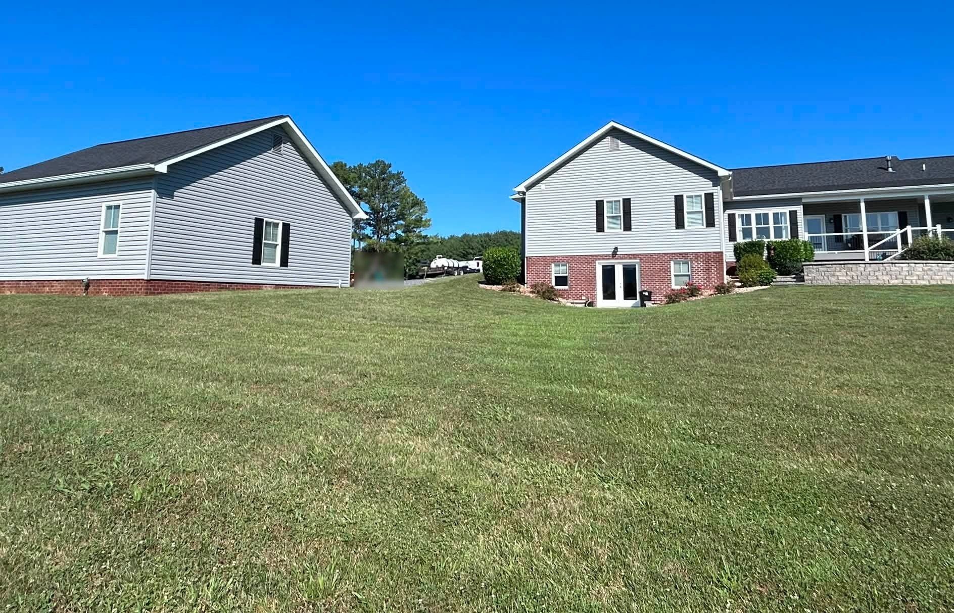 Gray-sided house and detached garage after a full exterior wash