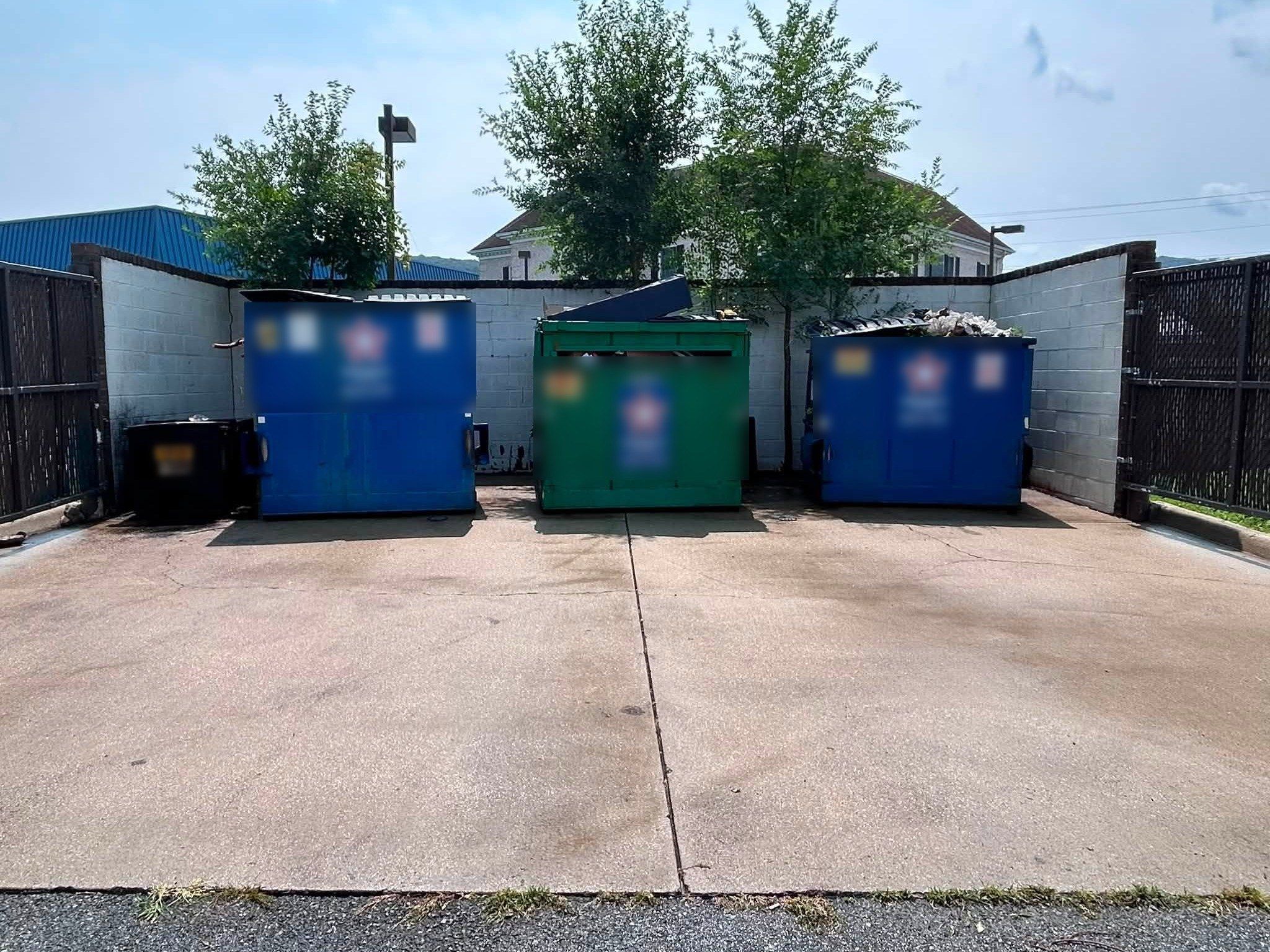 The same concrete dumpster pad, lighter and clean after pressure washing