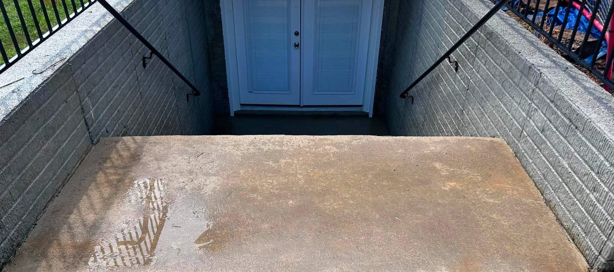 Washed concrete slab at the top of a basement stairwell, still wet