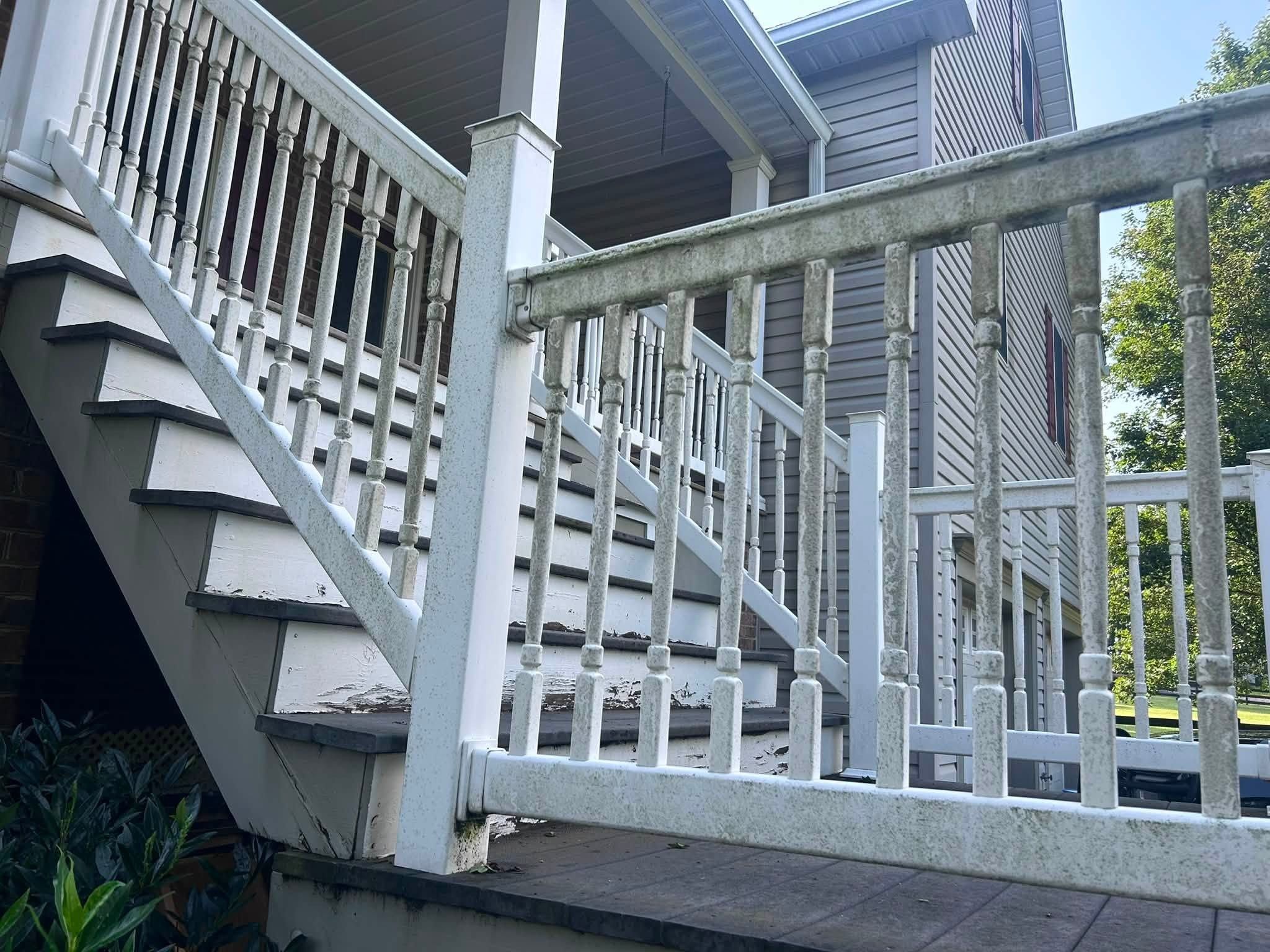 White porch stair railing and balusters coated green with algae