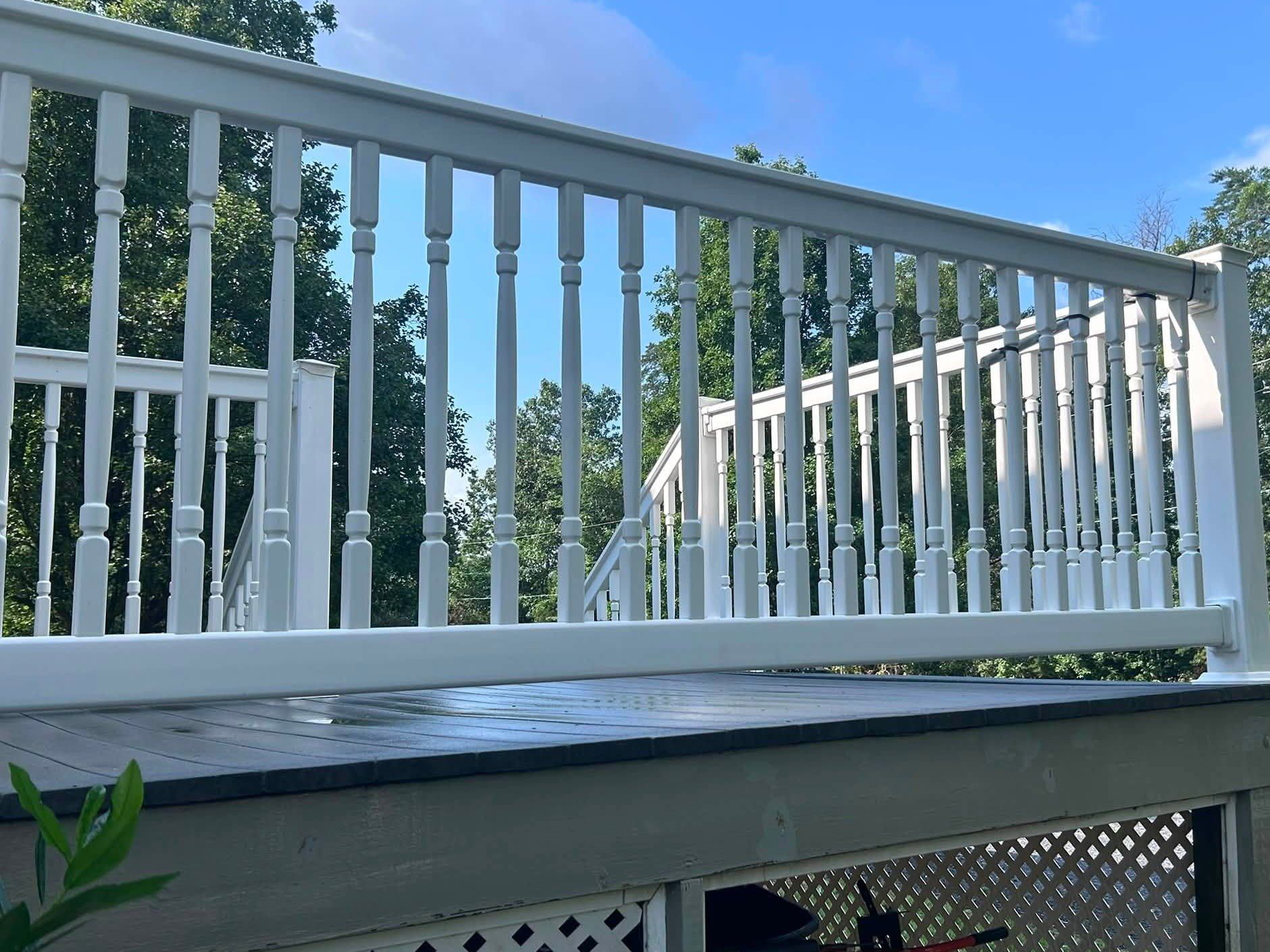 The same vinyl deck railing bright white after washing, seen from below the deck