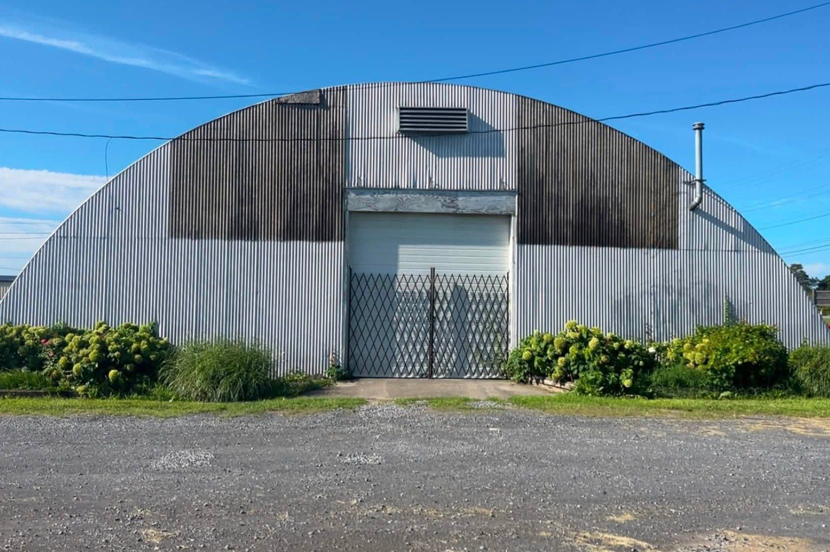 Corrugated metal building end wall with heavy black streaks on the upper panels
