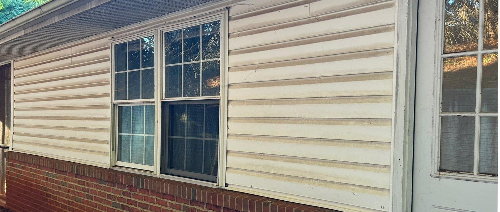Cream vinyl siding over a red brick base, stained with brown bands along every lap