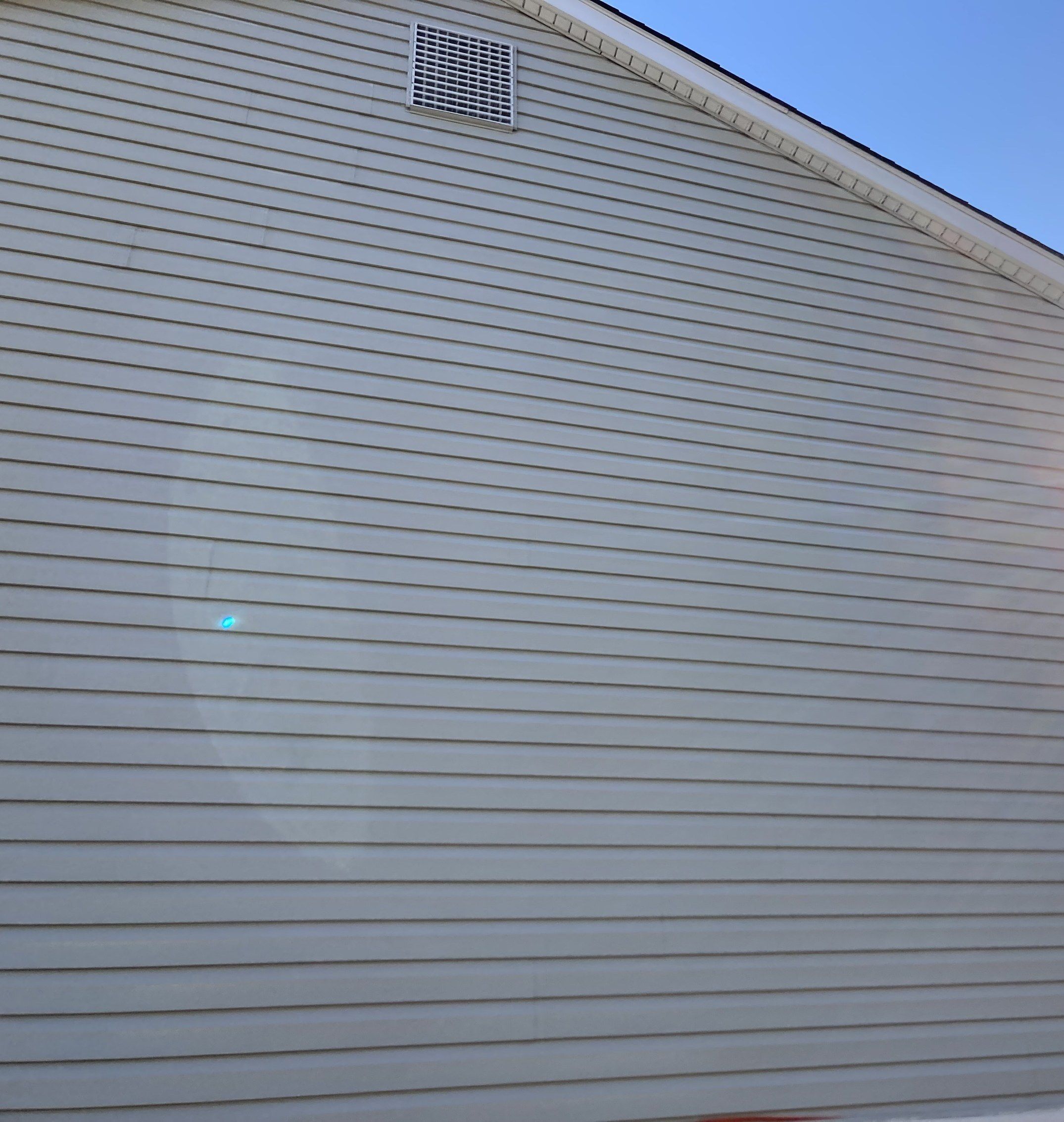That gable end's gray vinyl siding, even and clean after a soft wash